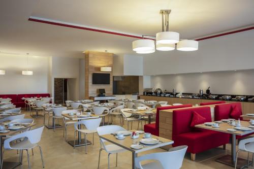 une salle à manger avec des tables et des chaises rouges dans l'établissement Fiesta Inn Celaya Galerias, à Celaya