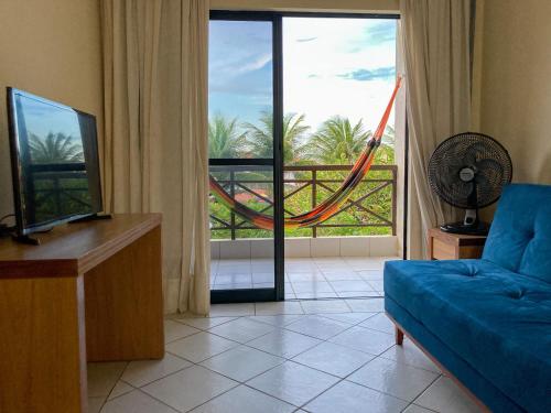 a living room with a couch and a window with a hammock at Vilamar Suítes in Aquiraz