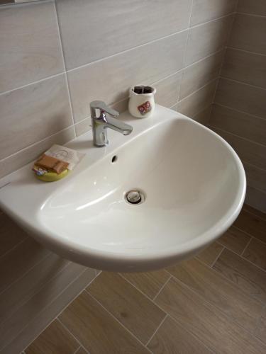 - un lavabo blanc dans la salle de bains avec une tasse dans l'établissement Strada Facendo, à Collebrincioni