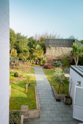 a backyard with a garden with palm trees and a wall at Hôtel Traiteur Les Ormes, The Originals Relais in Barneville-Carteret