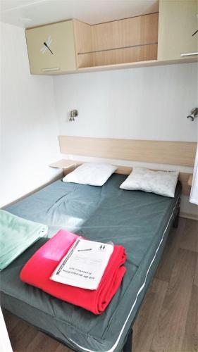 - un lit avec une couverture rouge dans l'établissement MOBIL HOME 4 PERSONNES TOUT CONFORT, à Port-la-Nouvelle
