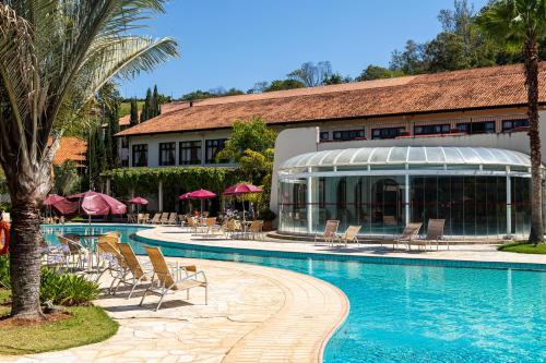 un complexe avec une piscine entourée de chaises et un bâtiment dans l'établissement Villa di Mantova Resort Hotel, à Águas de Lindóia