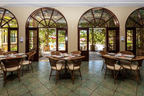 uma sala de jantar com mesas, cadeiras e janelas em Villa di Mantova Resort Hotel em Águas de Lindoia