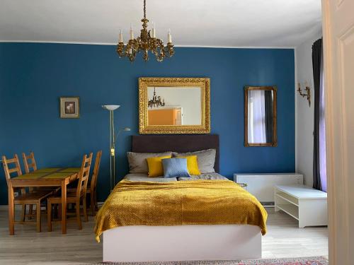 a bedroom with a blue wall with a bed and a table at Kamienica Monte Cassino Sun I 7 min plaża I 2 sypialnie I Balkon in Sopot