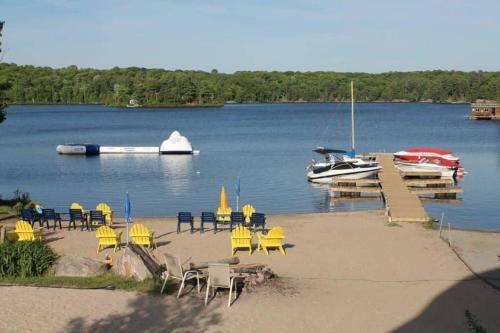 una playa con sillas y un barco en el agua en Bunkie 4 At The Lake On Muskoka Shores, en Otter Lake
