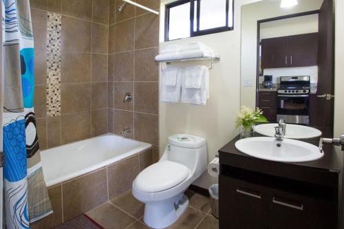 a bathroom with a toilet and a sink and a tub at Villa Vista Hermosa - with breathtaking ocean view & WiFI in Quepos