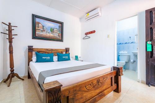 a bedroom with a wooden bed with blue pillows at Hotel Colonial La Casa De Siempre in Valledupar