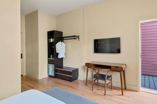 1 dormitorio con escritorio y TV en la pared en The Francis Hotel, en Portland