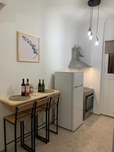 eine Küche mit einem Tisch mit Weinflaschen und einem Kühlschrank in der Unterkunft ''Korifo apartment'' at Benitses in Benitses