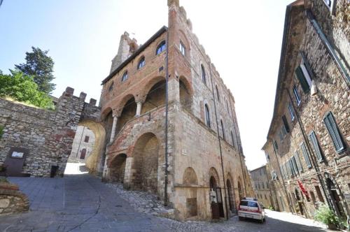 un vieux bâtiment en brique avec une voiture garée à côté dans l'établissement La casa di Lisa, à Suvereto