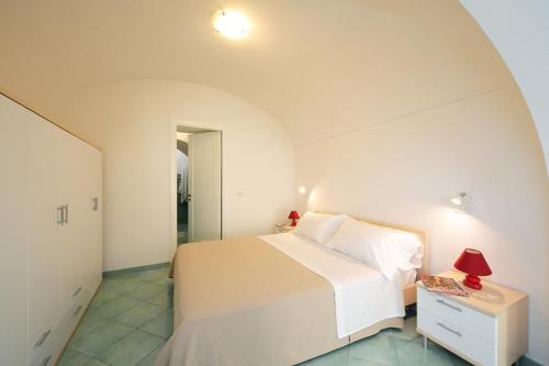 um quarto com uma cama branca e uma mesa com um candeeiro em Campolillo House em Amalfi