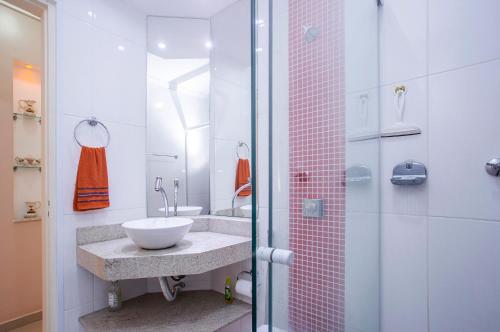 a bathroom with a sink and a glass shower at Apartamento Águas de Lindoia in Águas de Lindóia
