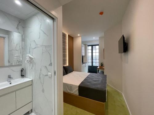 a bathroom with a bed and a shower and a sink at MyStay Porto São Bento in Porto
