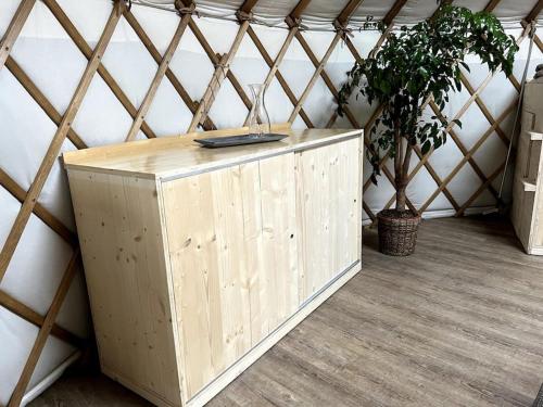 a wooden cabinet in a yurt with a plant at Jurte beim Lama- & Alpakahof Triesenberg in Triesenberg