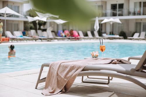 a table with a towel on it next to a swimming pool at TUISuneo La Conchiglia - Adults Only in Capo Vaticano