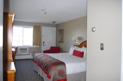 a hotel room with a bed and a red chair at South Hill Lodge in Prince Albert