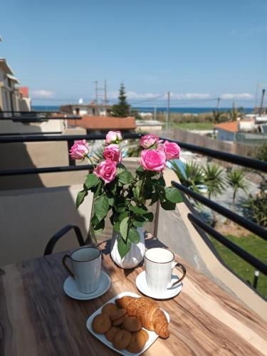 a table with a vase of pink roses and cookies at Secret Garden Hotel in Maleme