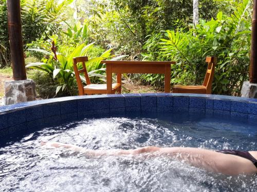 a person laying in a hot tub in a backyard at Hosteria La Roulotte - Mindo in Mindo