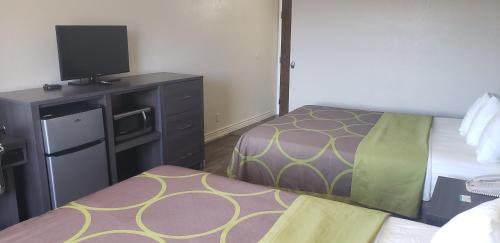 a hotel room with two beds and a flat screen tv at Super 8 by Wyndham Goodyear/Phoenix Area in Goodyear
