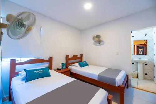 a bedroom with two beds and a fan at Hotel Nuevo Yalu in Barranquilla
