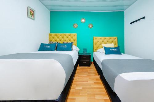 two beds in a room with blue and green walls at Ayenda Portal del Cable in Manizales