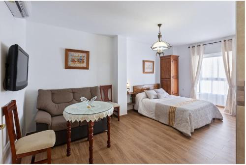 - un salon avec un lit, un canapé et une table dans l'établissement Apartamento en Olvera, à Olvera
