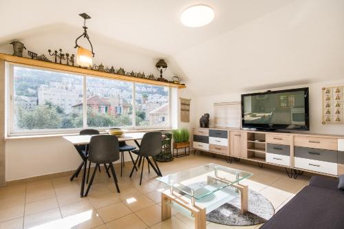 a living room with a table and a tv at Amazing view Bahai gardens - german colony center in Haifa