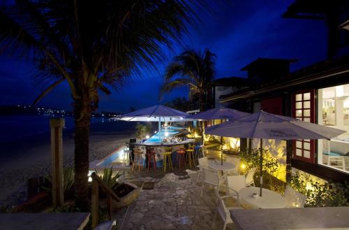 a restaurant with tables and umbrellas on the beach at night at Chez Pitu Praia Hotel in Búzios