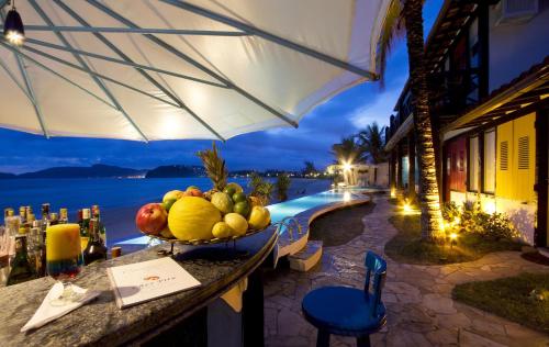 a bowl of fruit on a table next to a pool at Chez Pitu Praia Hotel in Búzios