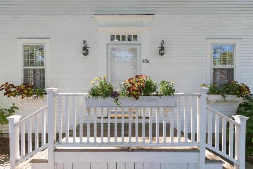 une maison blanche avec une véranda fleurie dans l'établissement 45B Pleasant St, à Nantucket