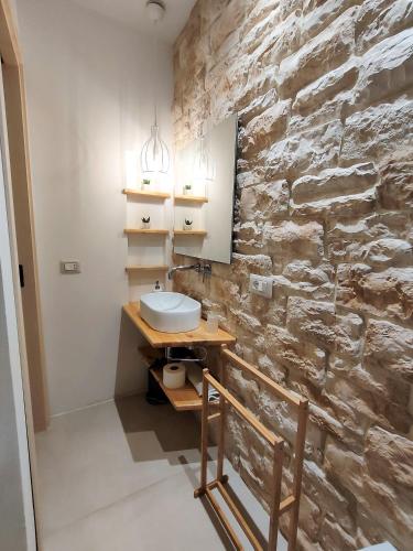 a bathroom with a sink and a stone wall at Appartamento Il Cappero in Modica