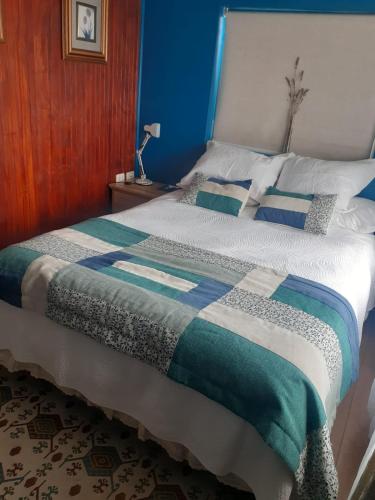 a bedroom with a bed with a blue and white comforter at Hostal Boutique "Maryluz" in Coihaique