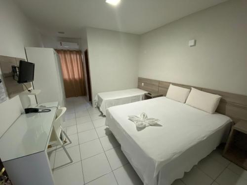 um quarto com uma cama branca com uma flor em Hotel Sabrina em Guanambi