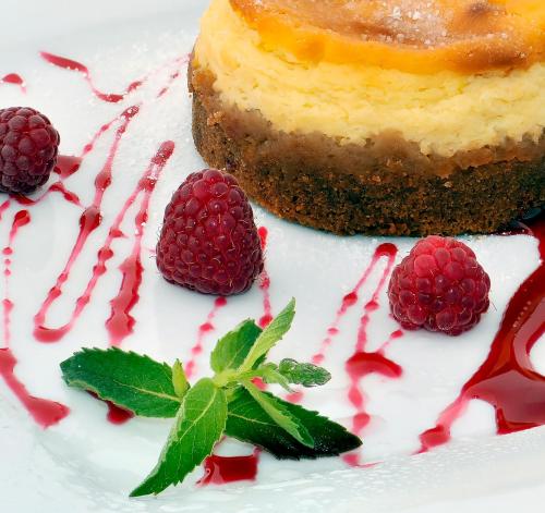 a white plate with a piece of cake and raspberries at Fontan in Chornomorsk