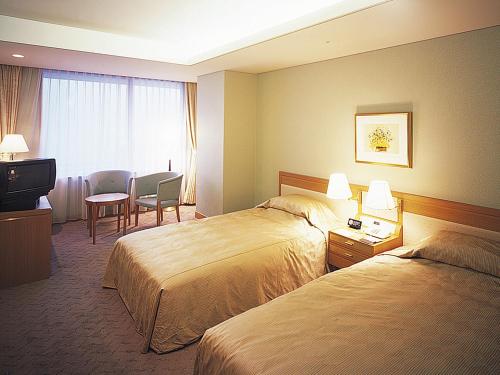 a hotel room with two beds and a television at Arima Onsen Gekkoen Korokan in Kobe