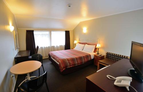 Habitación de hotel con cama, escritorio y mesa. en Sai Motels - Greenlane Auckland, en Auckland