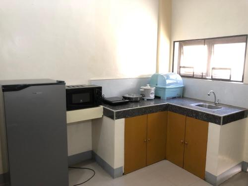 a small kitchen with a sink and a microwave at Door 1 Bench Apartment in Tacloban