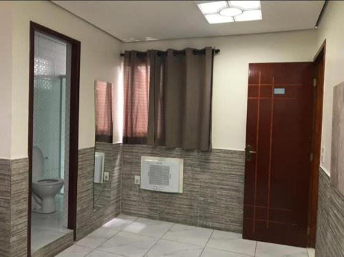 a bathroom with a toilet and a glass door at Hotel Caliente in Sao Paulo