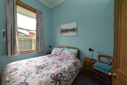 um quarto com uma cama, uma cadeira e uma janela em Southern Comfort em Invercargill