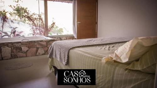 イビコアラにあるCasa dos Sonhosのベッドルーム1室(ベッド1台、バスタブ、窓付)