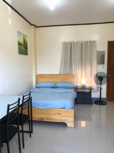 1 dormitorio con 1 cama, mesa y sillas en Door 8 Bench Apartment en Tacloban