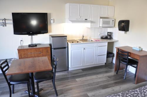 a kitchen with a table and a television and a kitchen with white cabinets at Moonlight Inn and Suites Sudbury in Sudbury
