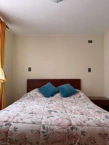 a bedroom with a bed with two blue pillows on it at Cabañas Maihue in La Serena