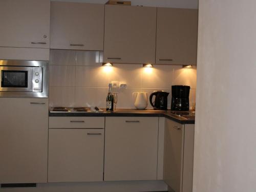 a kitchen with white cabinets and a microwave at Nice apartment with terrace near the sea in Bray-Dunes