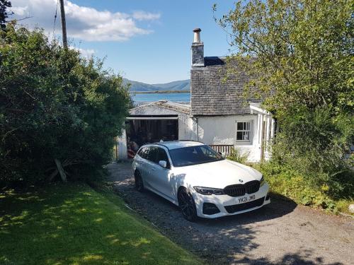 a white car parked in front of a house at The Old Ferryhouse in Port Appin