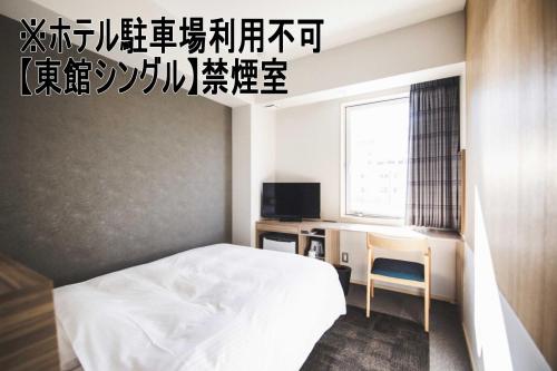 a bedroom with a bed and a desk and a television at Hotel Kajiwara in Matsuyama
