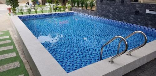 a swimming pool with blue tiles on the side of a building at Tc theme park Guest house in Kuantan