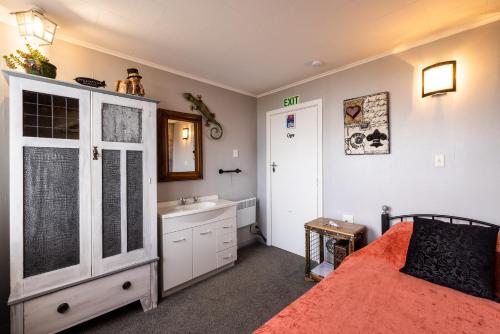 a room with a bed, a refrigerator, and a television at Oamaru Backpackers in Oamaru