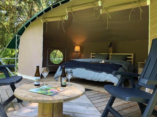 een slaapkamer met een bed en een tafel met 2 stoelen bij Camping Ardennes Insolites in Marbehan