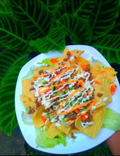 a plate of nachos with dressing and vegetables on it at Payag n' Kapitan, Experience pinubre living in Siquijor